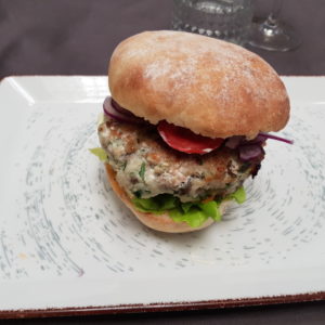 Burger de saumon, sauce tartare et pousse épinard, salade composée.