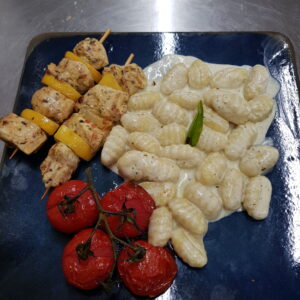 Brochette de poulet marinée au citron et thym, pâtes au pesto et tomates confites.